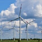 white wind turbines on green grass field under blue and white cloudy sky during daytime